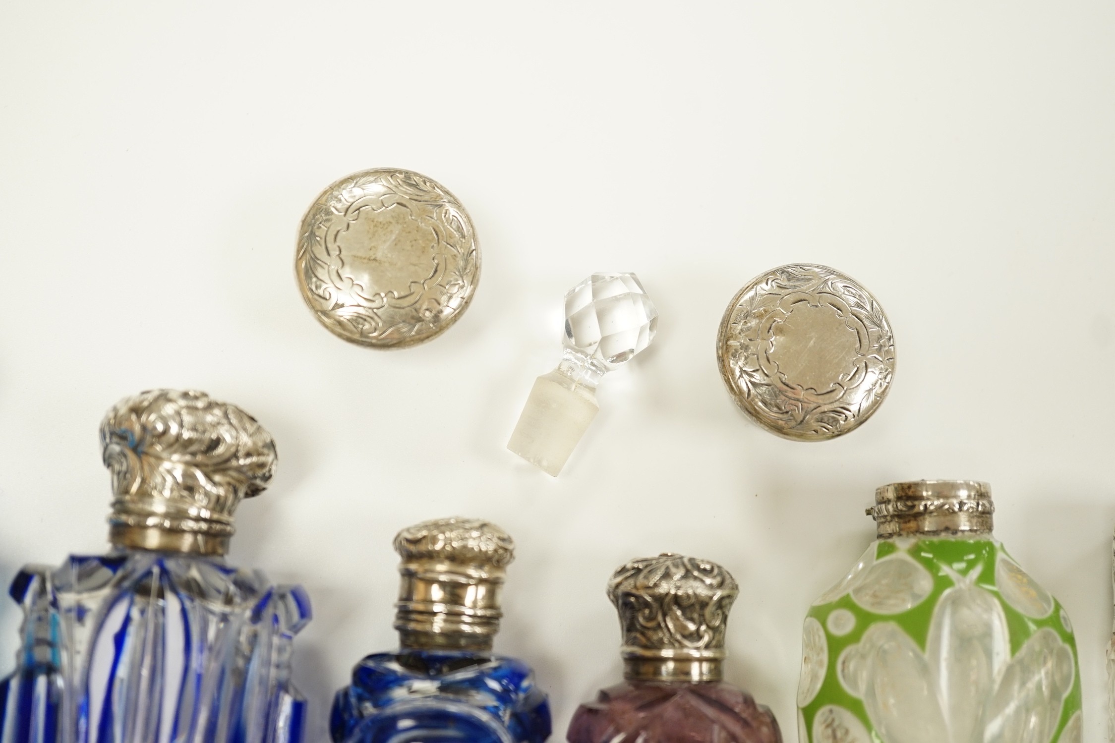 A late Victorian silver mounted cut glass scent bottle, Charles Boyton II, London, 1896, 82mm and six other late 19th/early 20th century, silver or white metal mounted coloured cut glass scent bottles (some a.f.) and two